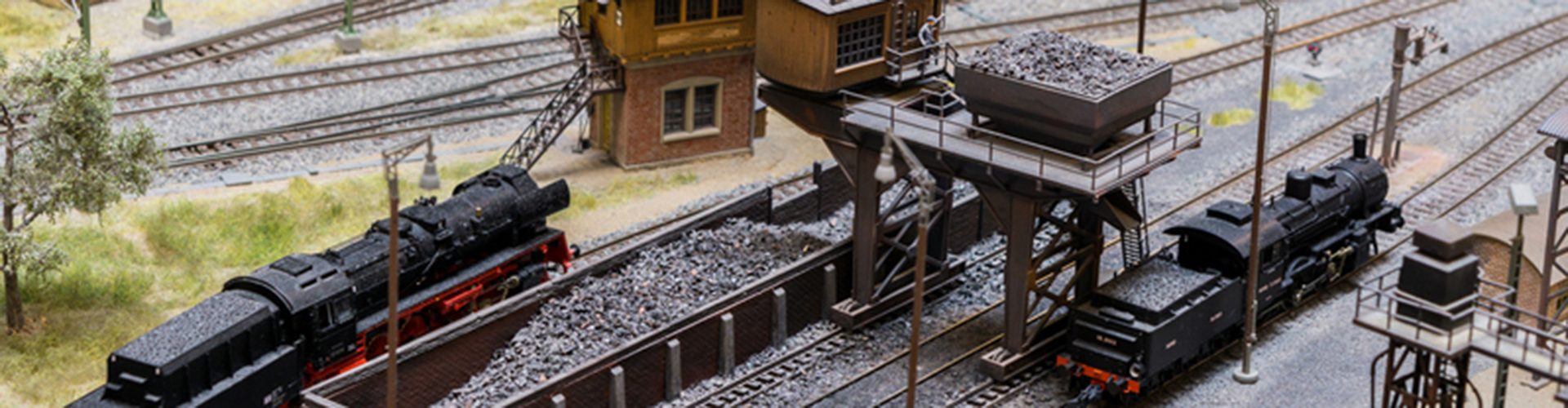 Models of railway steam engine locomotives and coal wagons waiting at recharging station